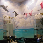 Hand Painted Custom Murals. a masterbath vanity area showing a mural of blue sky, aqua water, and florida birds flying overhead.