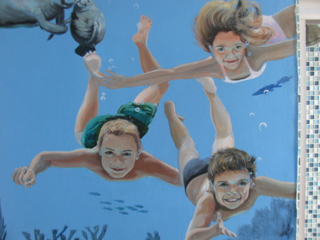 Hand Painted Custom Murals. this mural shows three children swimming under the water toward the observer