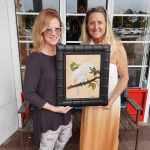 Martha Dodd on the right with Marti Koehler holding her newly purchased painting of a cockatoo.